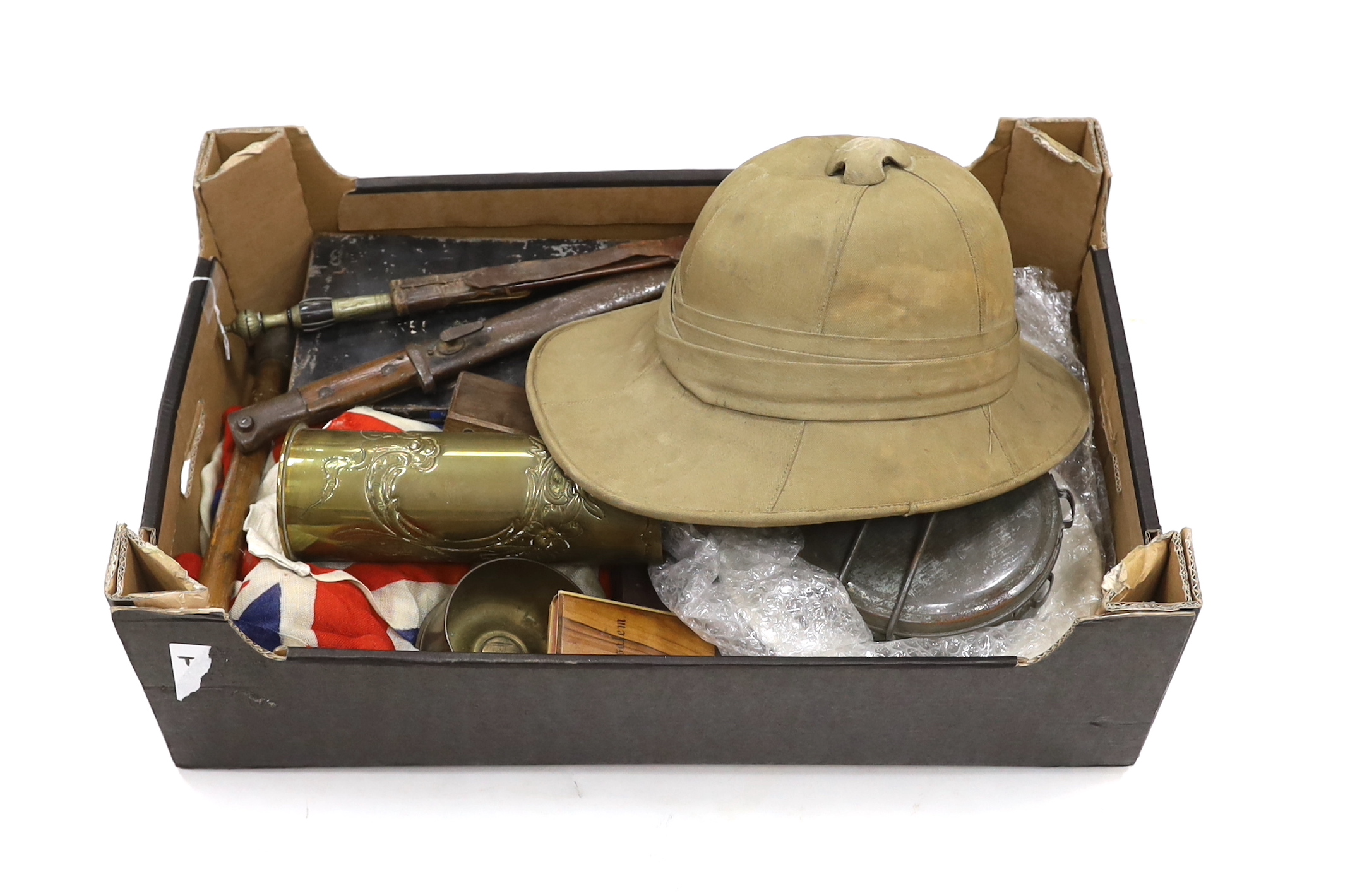 A collection of militaria including; a pith helmet, a T.G. Co. Ltd. Mk.III compass, a cased protractor, a Union flag, a trench art shell casing, a bayonet, an Indian knife, a mess plate with ERII cypher, etc.